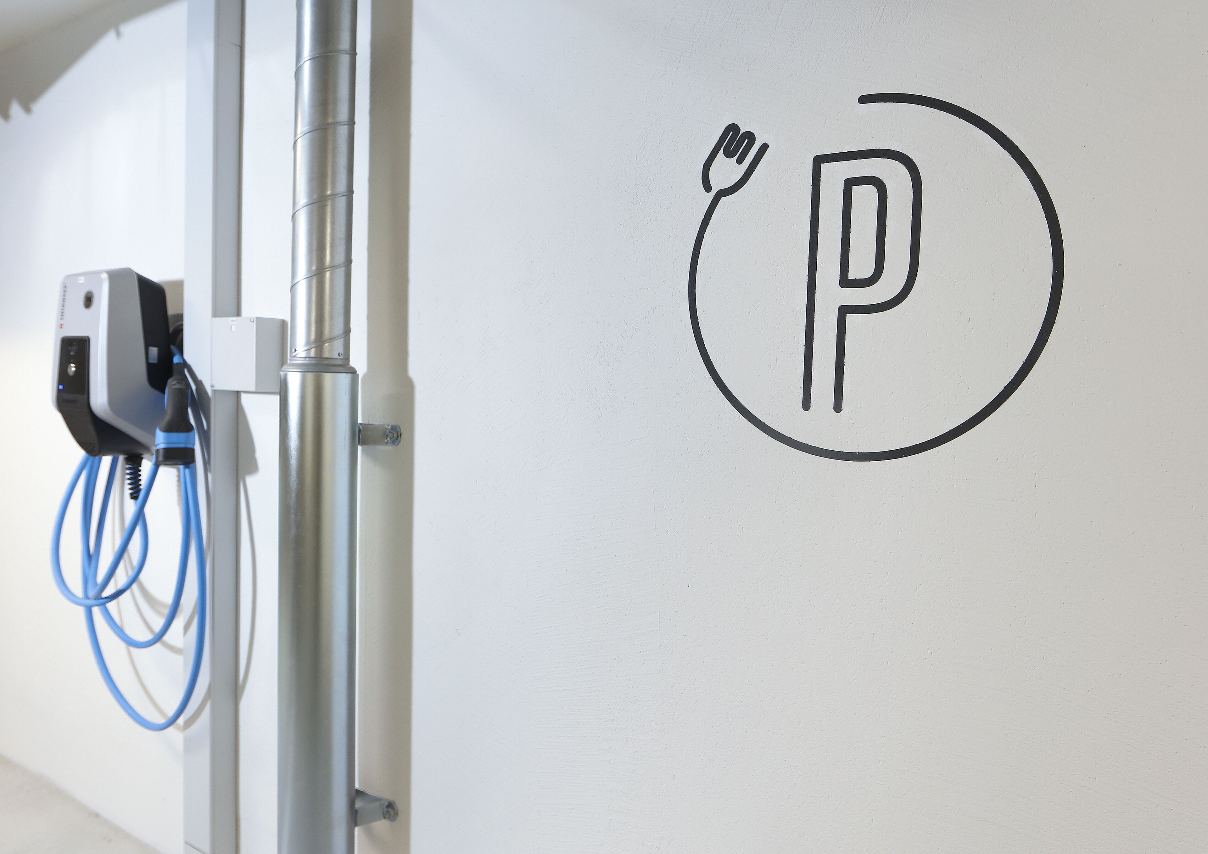 A wall-mounted electric vehicle charging station with a plug and a cord.