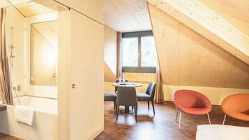 A modern, wooden interior with a small dining area, two chairs, and a view through a window.
