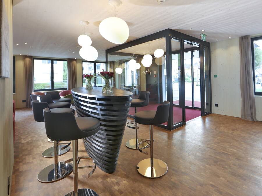 Een moderne bar met een opvallend gebogen ontwerp, verschillende zithoeken en uitzicht op het buitenlandschap door grote ramen.