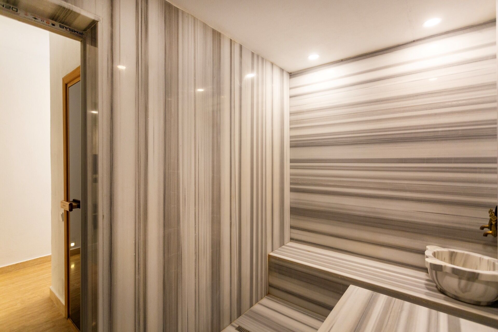 A modern bathroom with a marble wall, a sink, and a shower area.