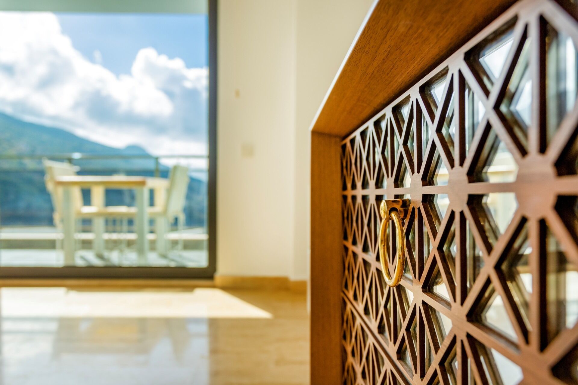 A room with a wooden partition and a large window with a view of mountains and a table with chairs.