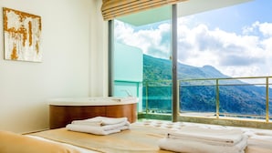 Une salle de bain moderne équipée d’une baignoire, d’un lavabo et d’une grande fenêtre donnant sur les montagnes.