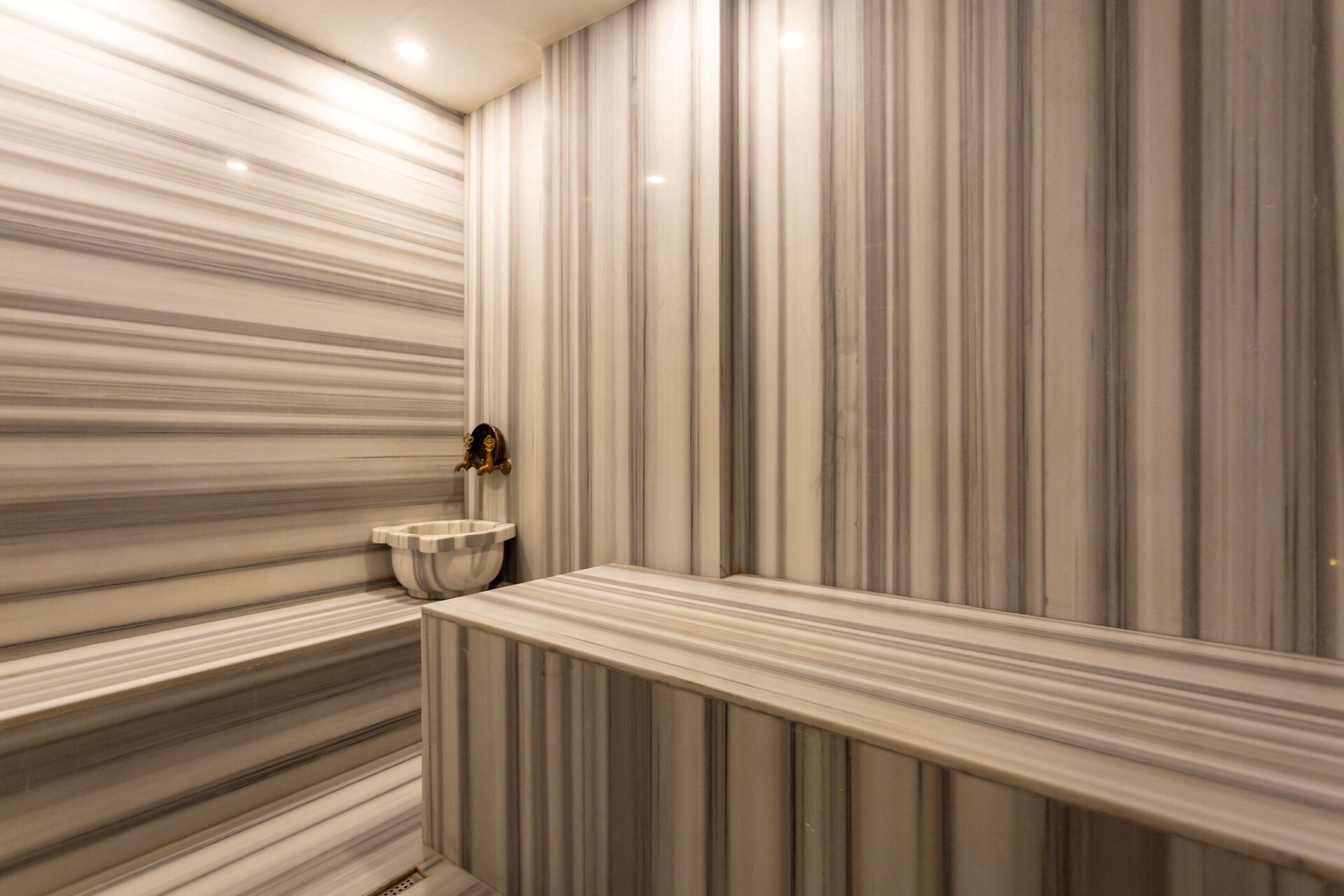 Une salle de bain avec un mur en marbre et un lavabo.