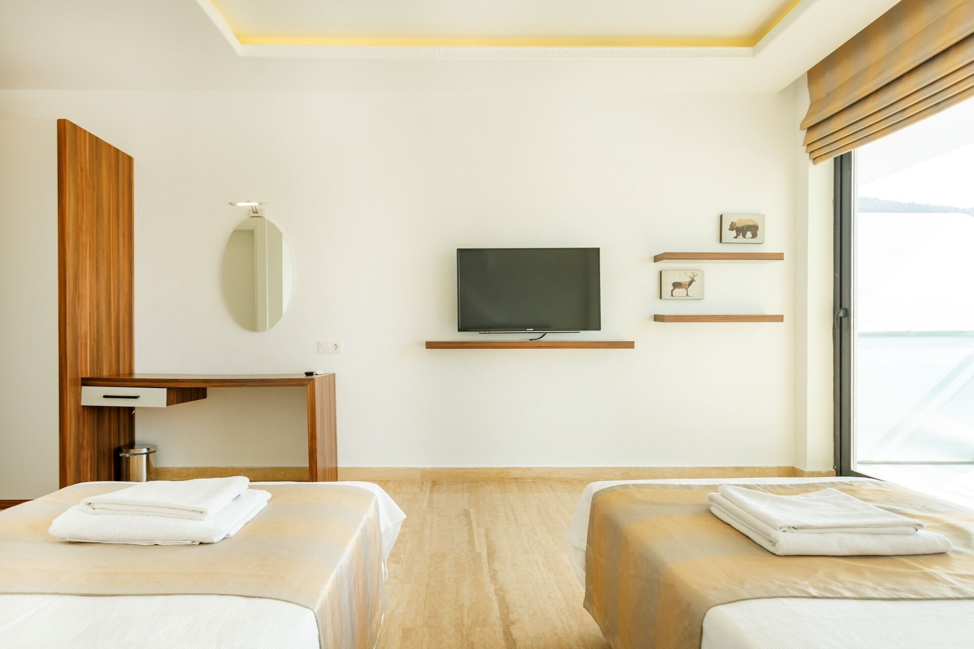 Een hotelkamer met twee bedden, een televisie, een spiegel en een klein bureau.