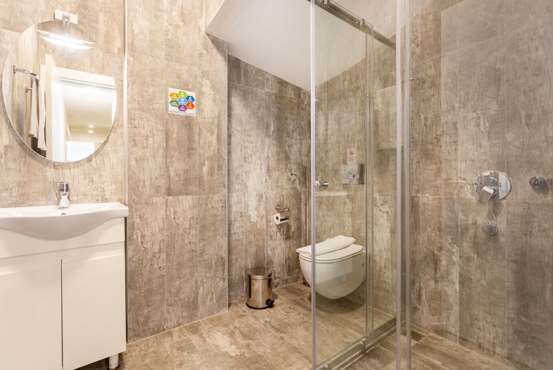 A bathroom with a sink, mirror, toilet, and shower area.