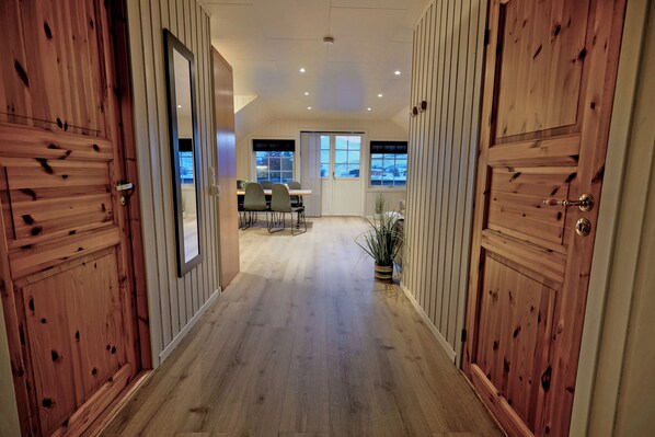 A hallway with wooden paneling and a dining area in the background. - XLyngen (Lyngen)