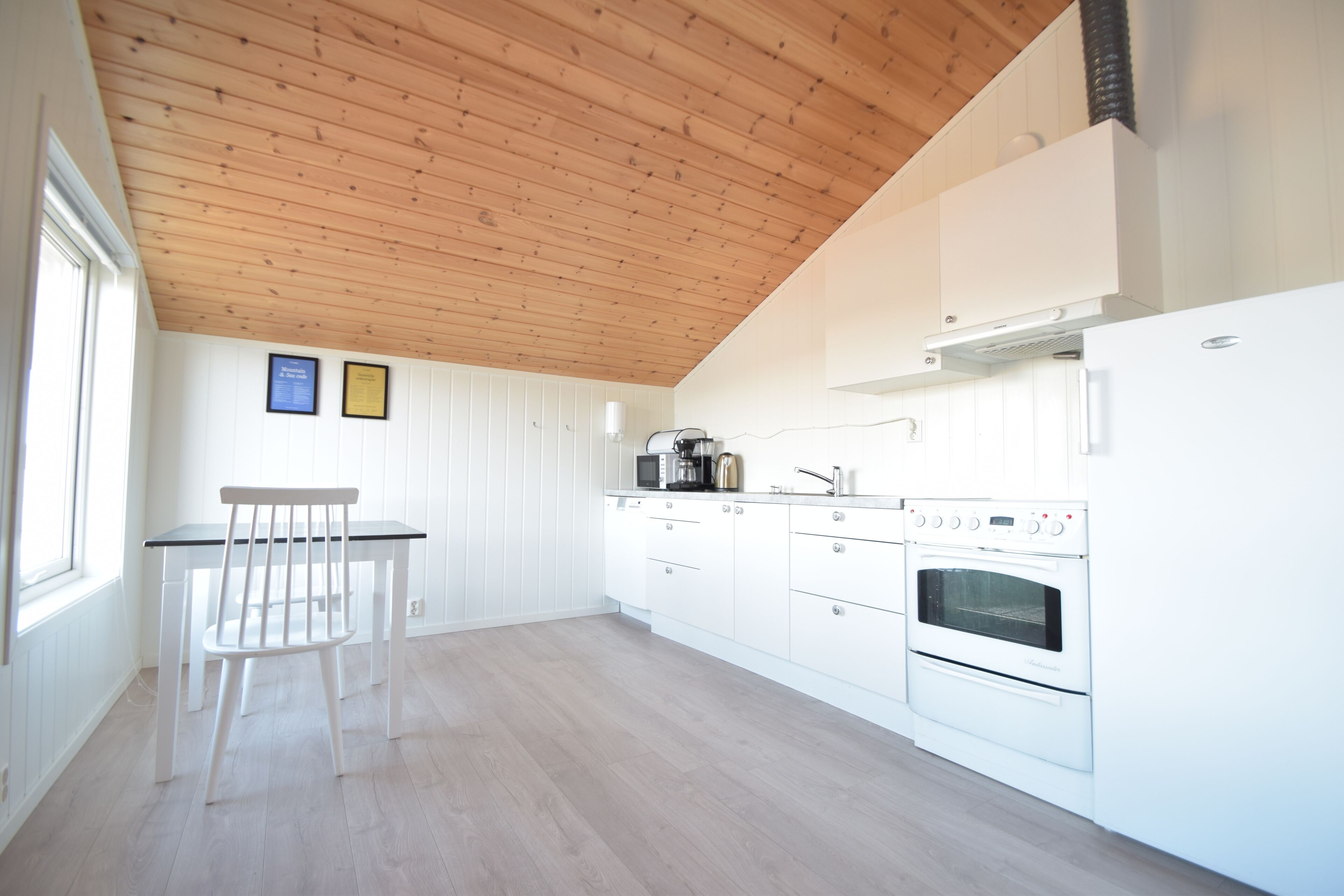 A kitchen with white cabinets, a wooden ceiling, and a window.