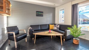 Un salon moderne avec un canapé en cuir noir, une table basse en bois et une plante en pot.