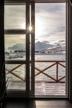 Una habitación con un gran ventanal que da a un paisaje nevado y un cuerpo de agua.
