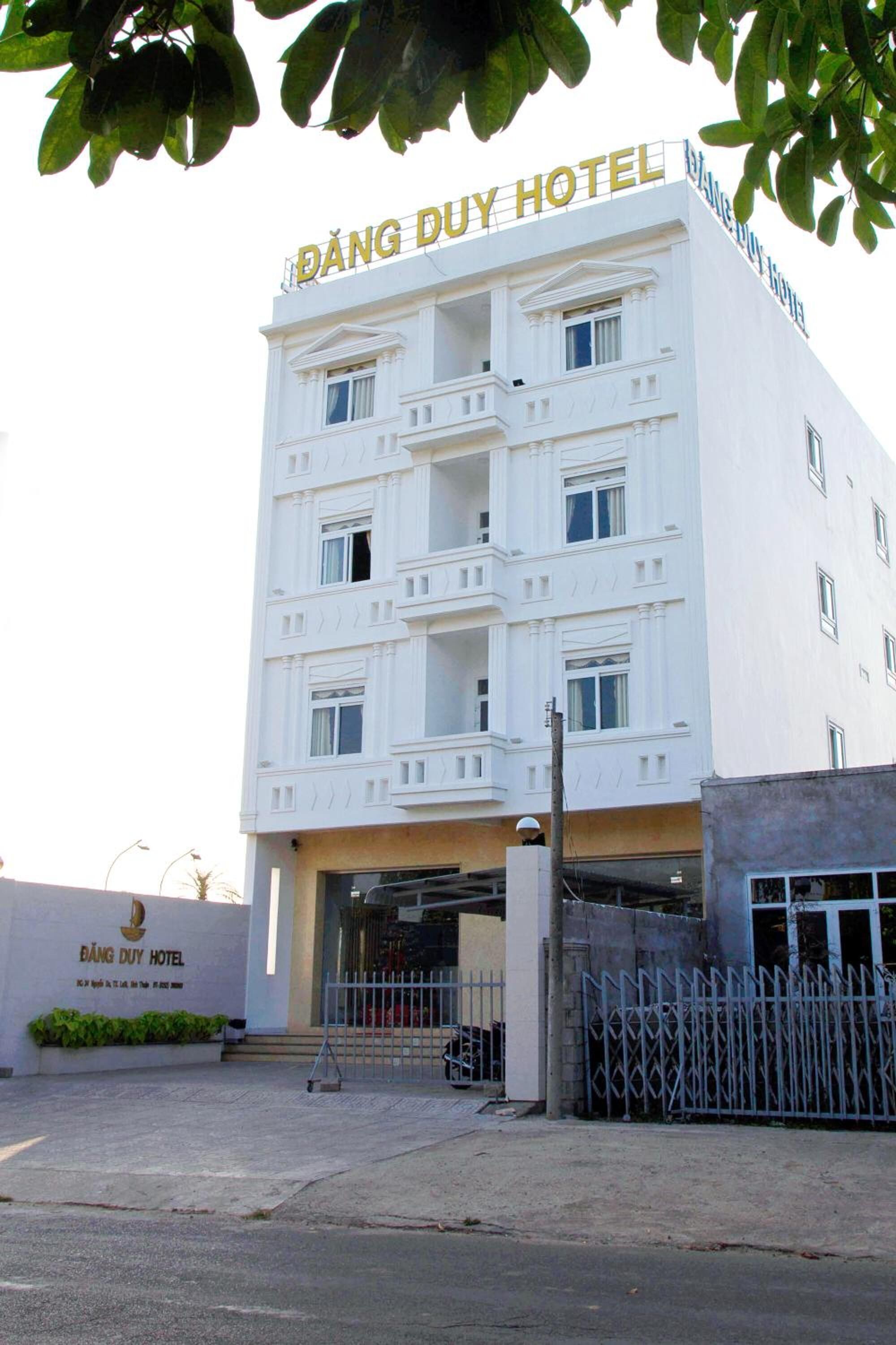 Un edificio blanco con el letrero "ĐÁNG DUY HOTEL" en la parte superior.