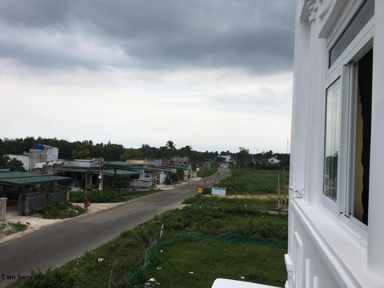 A view from a window overlooking a road with buildings and greenery.