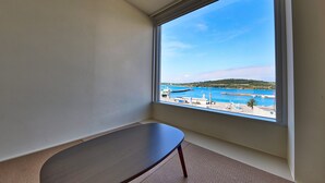 Una habitación con vista a la costa, una pequeña mesa de madera y un ventanal.