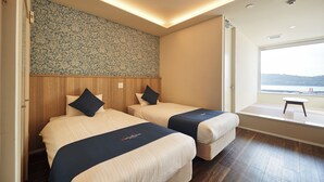 Habitación de hotel con dos camas, un cabecero de madera, pared con estampado y ventana con vistas.