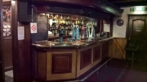 A bar area with a counter, shelves of bottles, and a no smoking sign. - Rhymney House hotel (Tredegar)