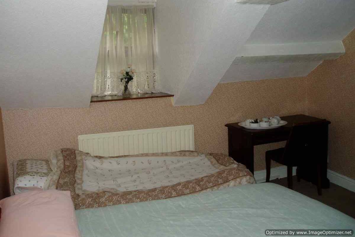 Une chambre avec un lit simple, une petite table avec une assiette et une chaise.