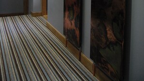 Un pasillo con alfombra a rayas, puertas de madera y una escalera.