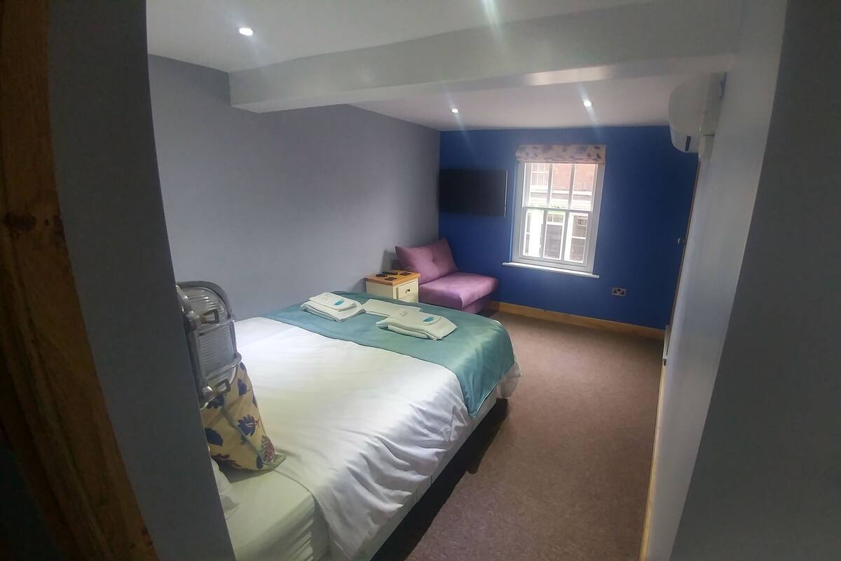 A bedroom with a bed, bedside table, and a window.