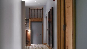 Un pasillo con alfombra a rayas, puertas de madera y una escalera con barandillas de madera.