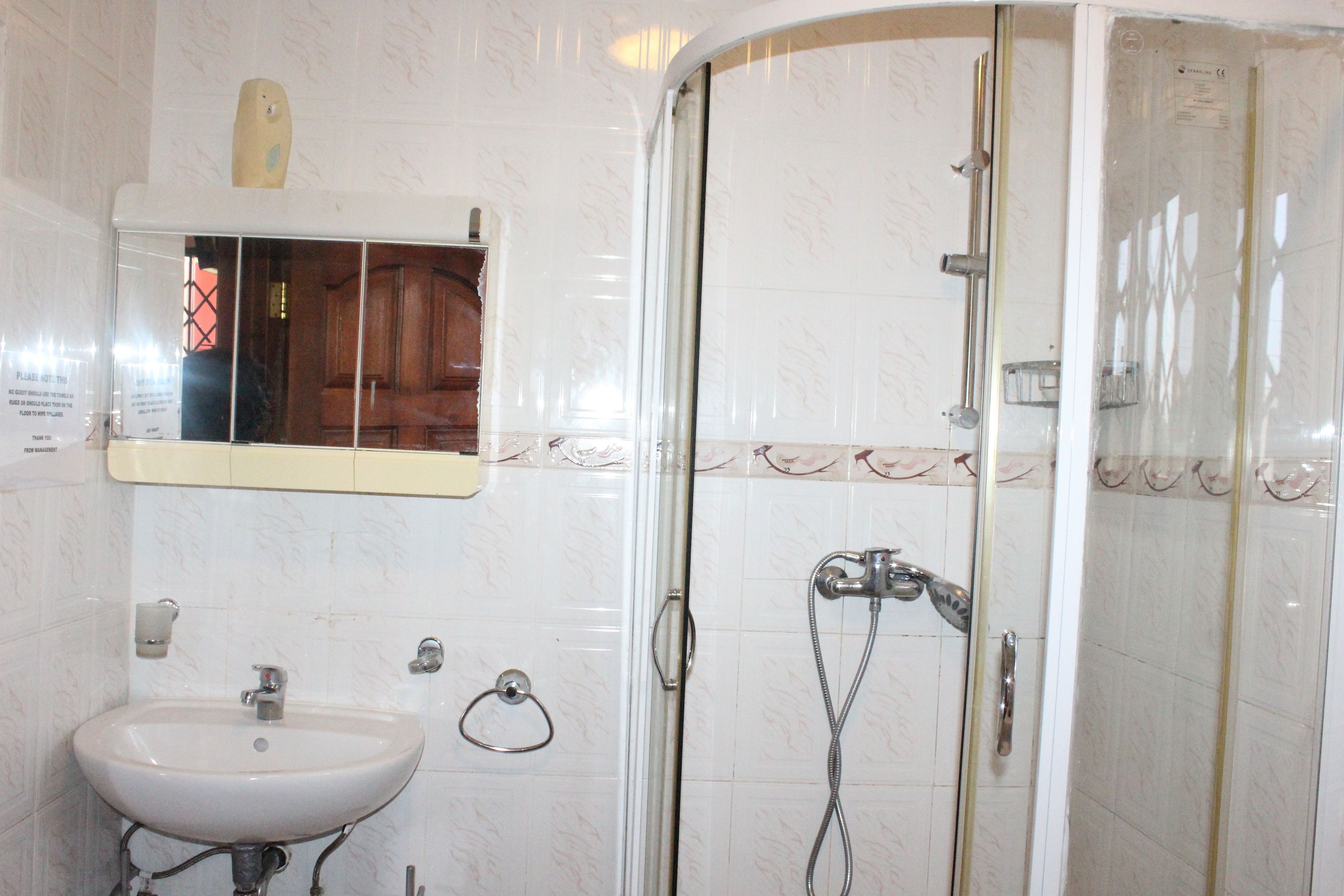A bathroom with a sink, mirror, and shower.