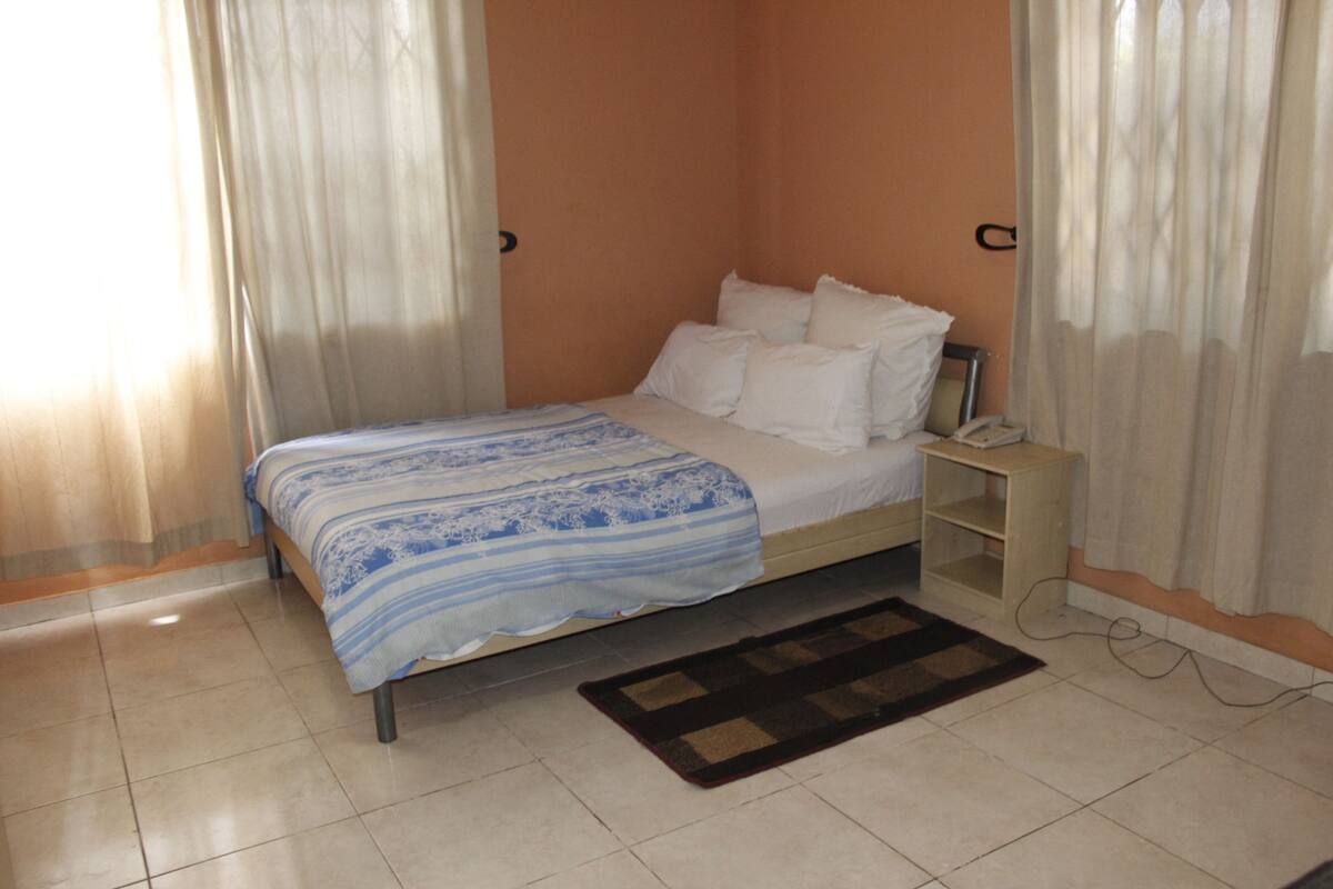 Un dormitorio con una cama, una mesita de noche, un teléfono y una alfombra.