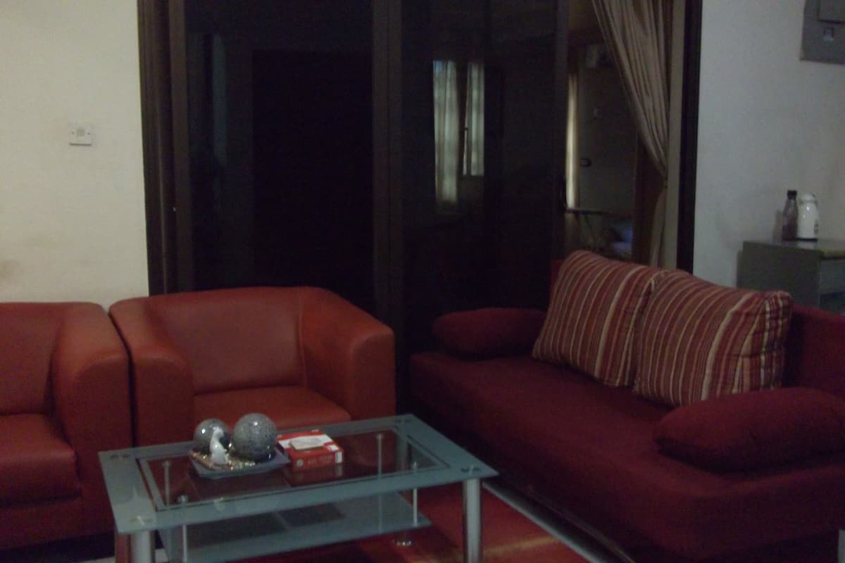Una sala de estar con un sofá rojo, una mesa de centro de vidrio y un cojín a rayas.