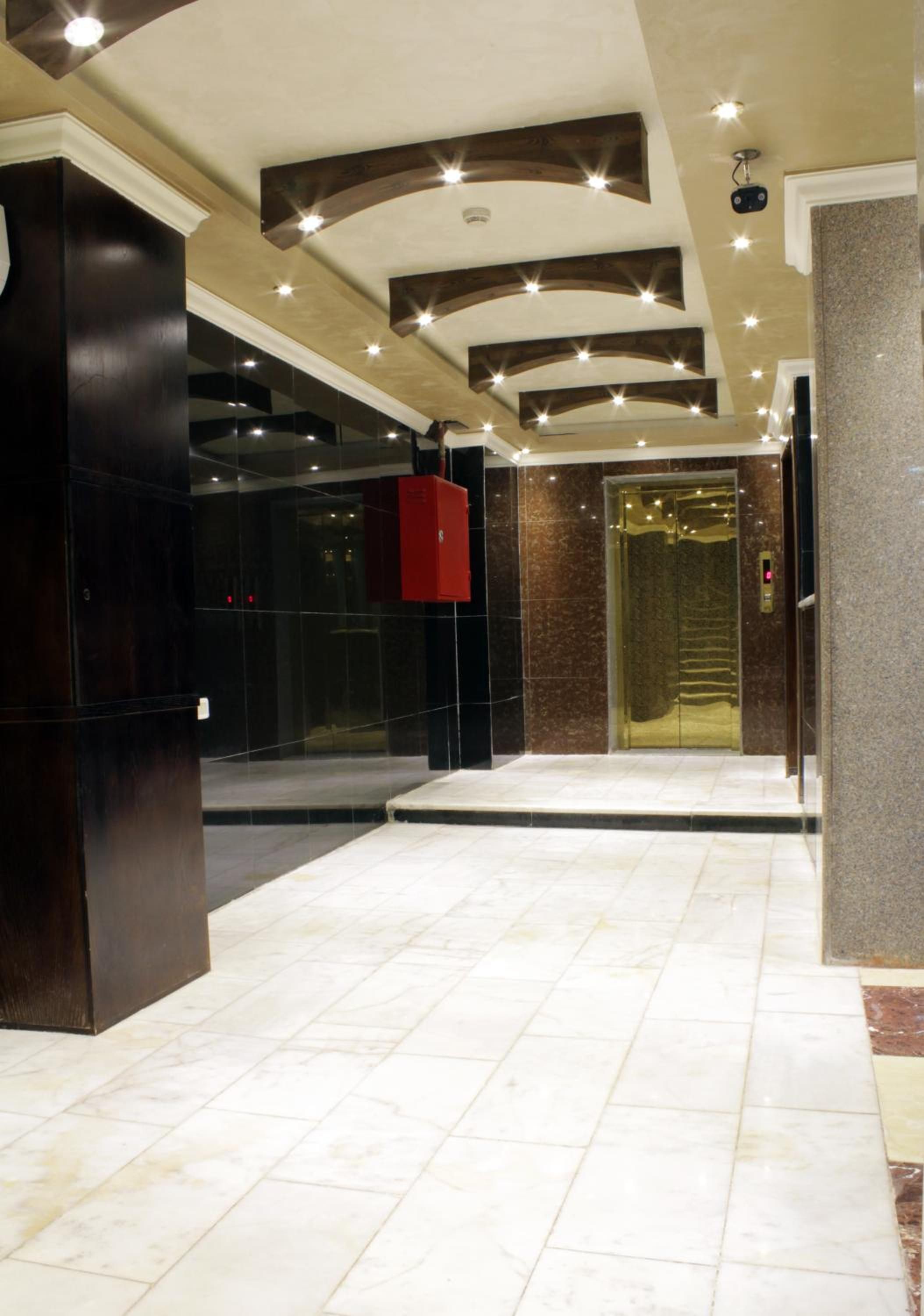 A lobby with a marble floor, a red elevator, and a modern ceiling design.
