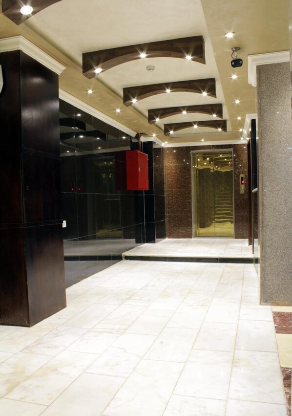 A lobby with a marble floor, a red elevator, and a modern ceiling design.