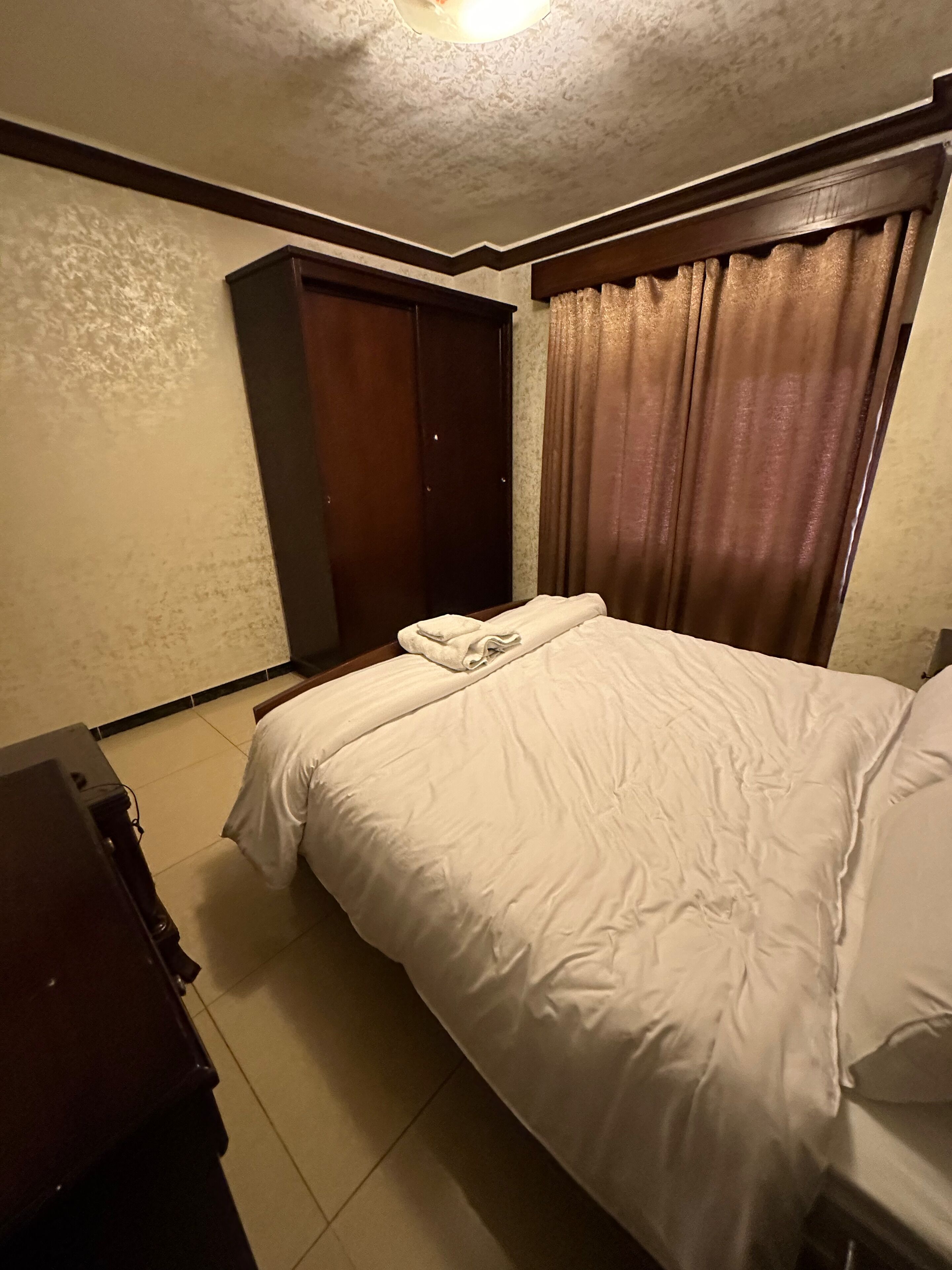 A hotel room with a bed, a wardrobe, and a desk.