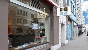 Une devanture de magasin avec une grande vitrine où l’on peut voir le nom « GOODMO » et les mots « MEILLEUR ÉTABLISSEMENT DE CHAMBRES D’HÔTES ».