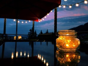 A glass jar with a light inside, placed on a reflective surface with string lights in the background. - AmstelSki Hotel (Bukovel)
