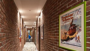 A hallway with brick walls, framed posters, and a patterned floor. - AmstelSki Hotel (Bukovel)