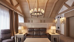 A modern living room with a leather sofa, two side tables with lamps, a wooden coffee table, and a chandelier. - AmstelSki Hotel (Bukovel)