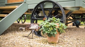 A birdhouse on a wooden structure with a wheel, a potted plant, and gravel ground. - Morndyke Shepherds' Huts (Thirsk)