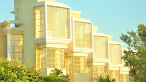 A multi-story building with large windows and a yellow facade. - Alcor Kumbhalgarh – the family getaway (Kumbhalgarh)