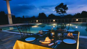 A dining table set for two with a pool in the background. - Alcor Kumbhalgarh – the family getaway (Kumbhalgarh)