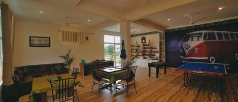A spacious living area with a ping pong table, a sofa, and a dining table.