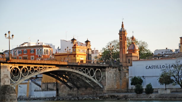 Un puente de piedra histórico con detalles de metal decorativos y un río debajo.