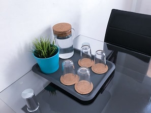 A minimalist space with a glass table, featuring a planter, a jar, and a tray with glass containers.