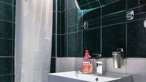 A bathroom with a white sink, a bottle of Bolea soap, and a shower curtain. - Charles Bridge Apartment (Prague)