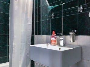 Bathroom features a sleek sink, mirror, and shower, with dark tile walls.