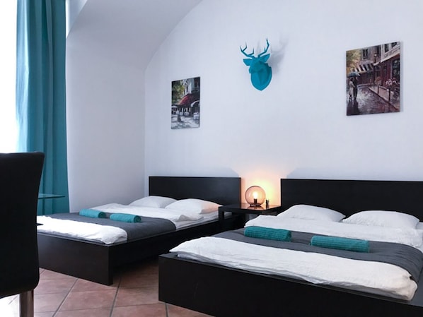 Two single beds with white bedding, a wall-mounted deer head, and framed artwork adorn this stylish room.