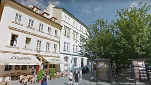 A cobblestone street with outdoor seating, a restaurant, and a bus stop. - Charles Bridge Apartment (Prague)