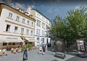 Stroll through historic streets lined with traditional European-style buildings, featuring outdoor seating areas and a tourist information center.