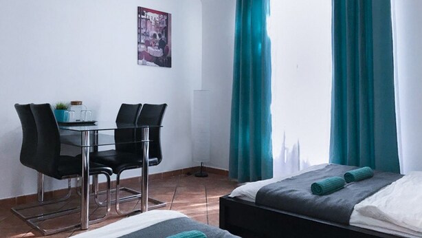 A room with a bed, a desk with chairs, and a window with curtains. - Charles Bridge Apartment (Prague)