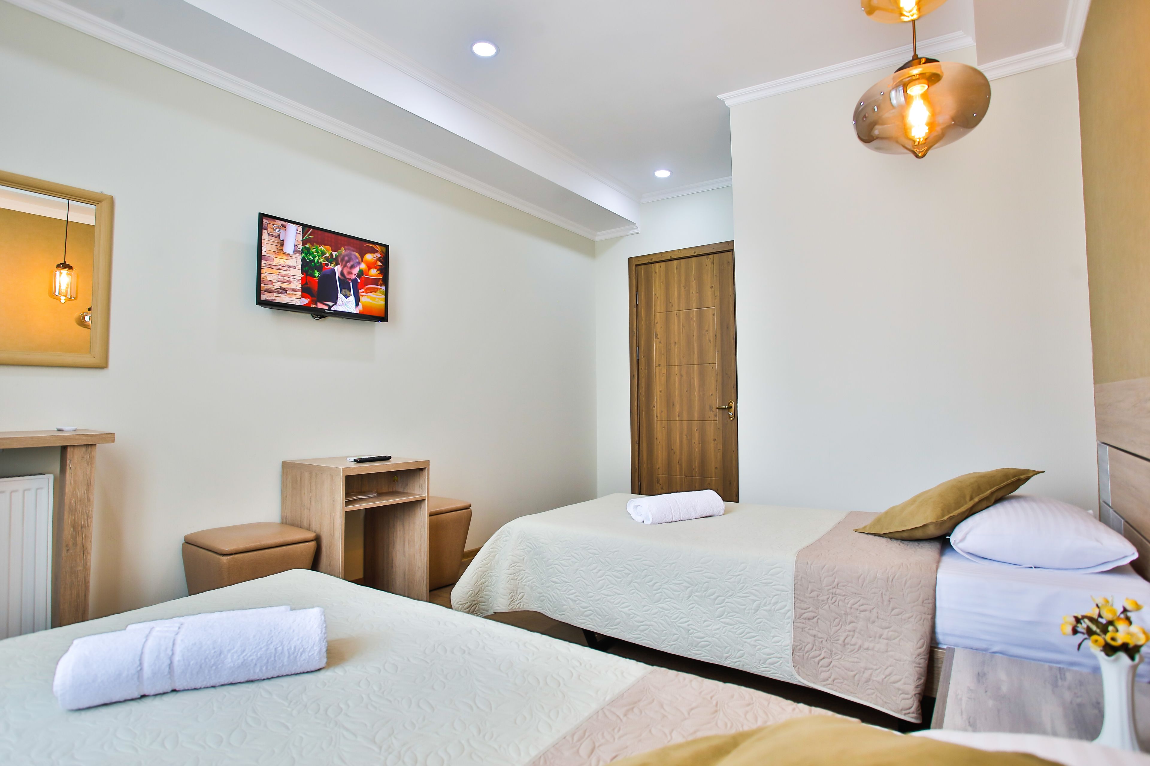 A hotel room with two beds, a wooden wardrobe, a television, and a small table.