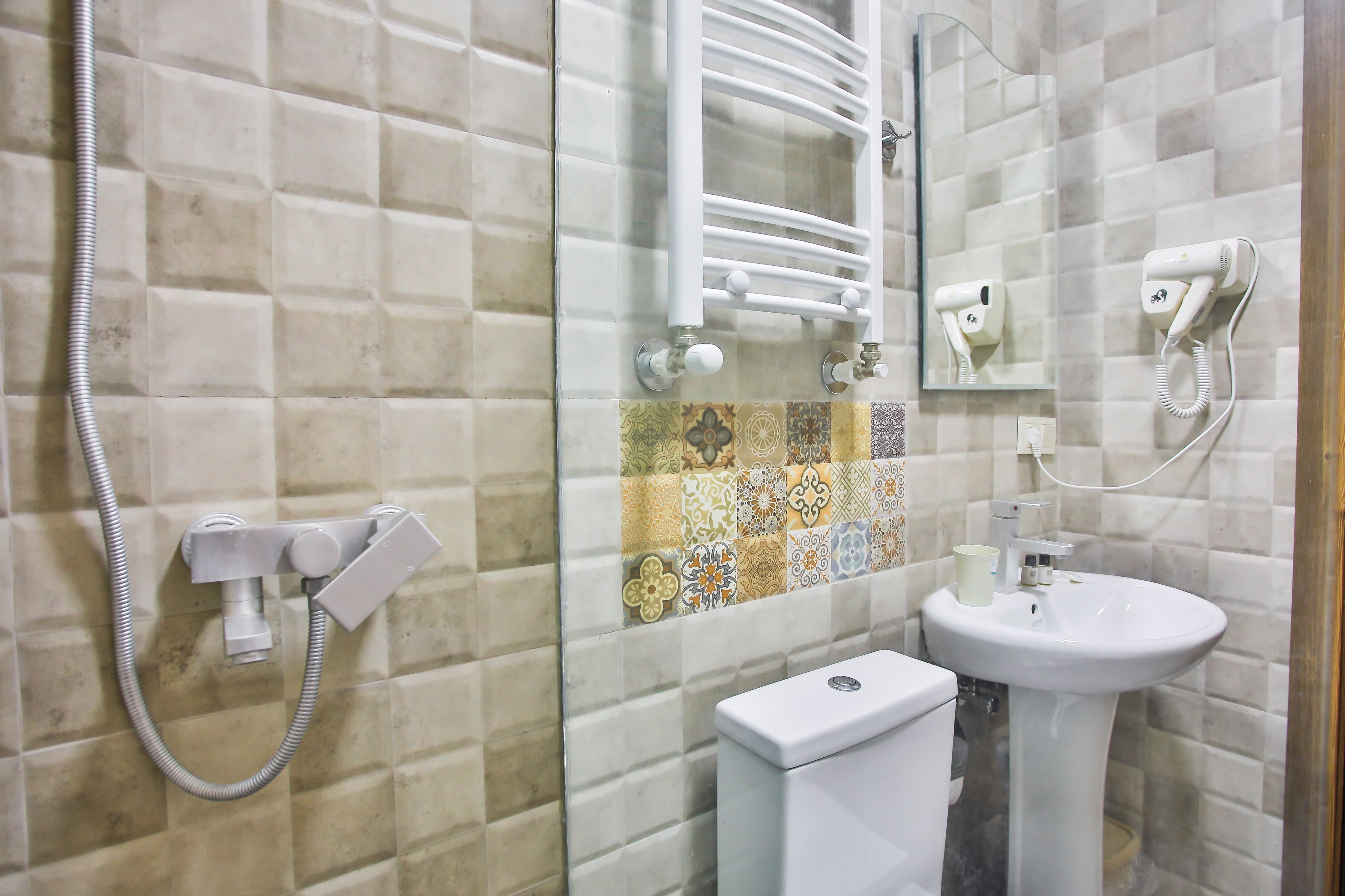 A bathroom with a shower, toilet, sink, and hairdryer.