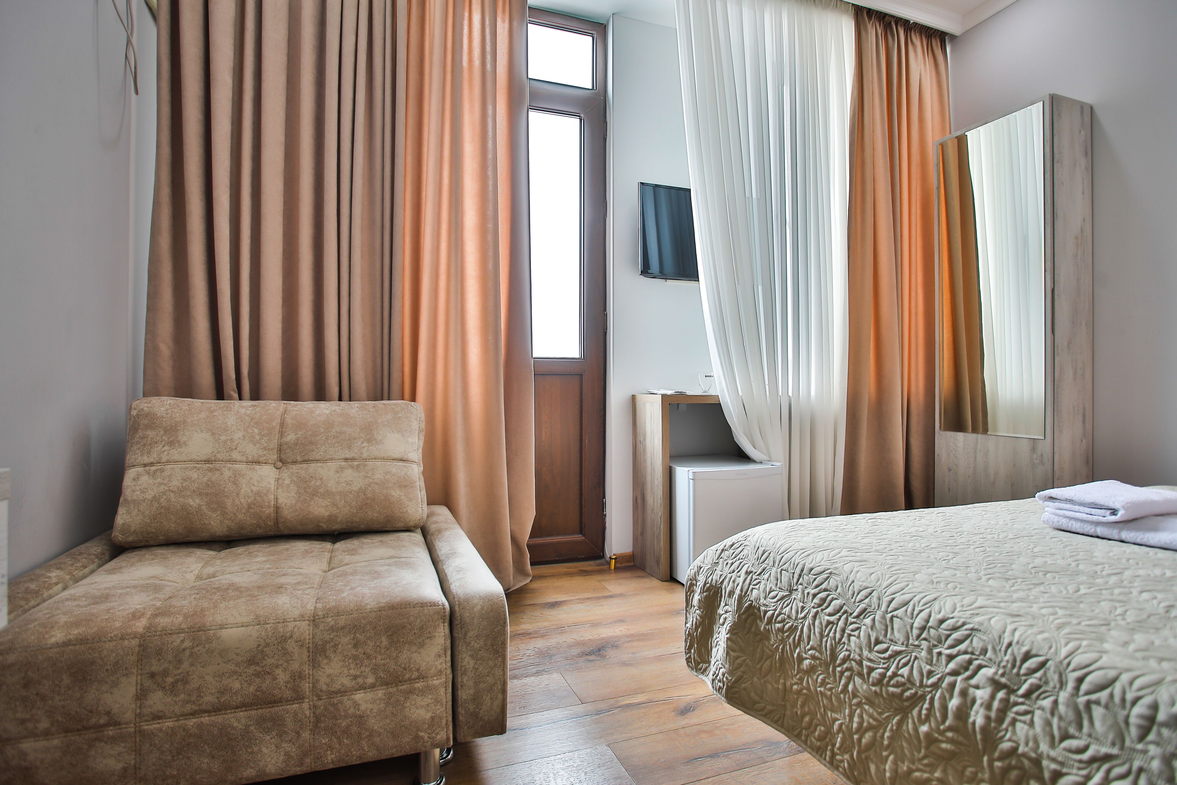 A hotel room with a sofa, a bed, a desk, and a large mirror.