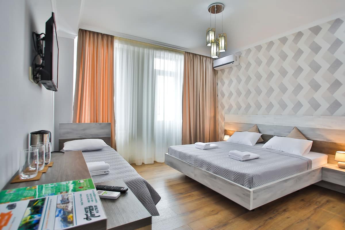 A hotel room with a bed, bedside table, and a TV mounted on the wall.