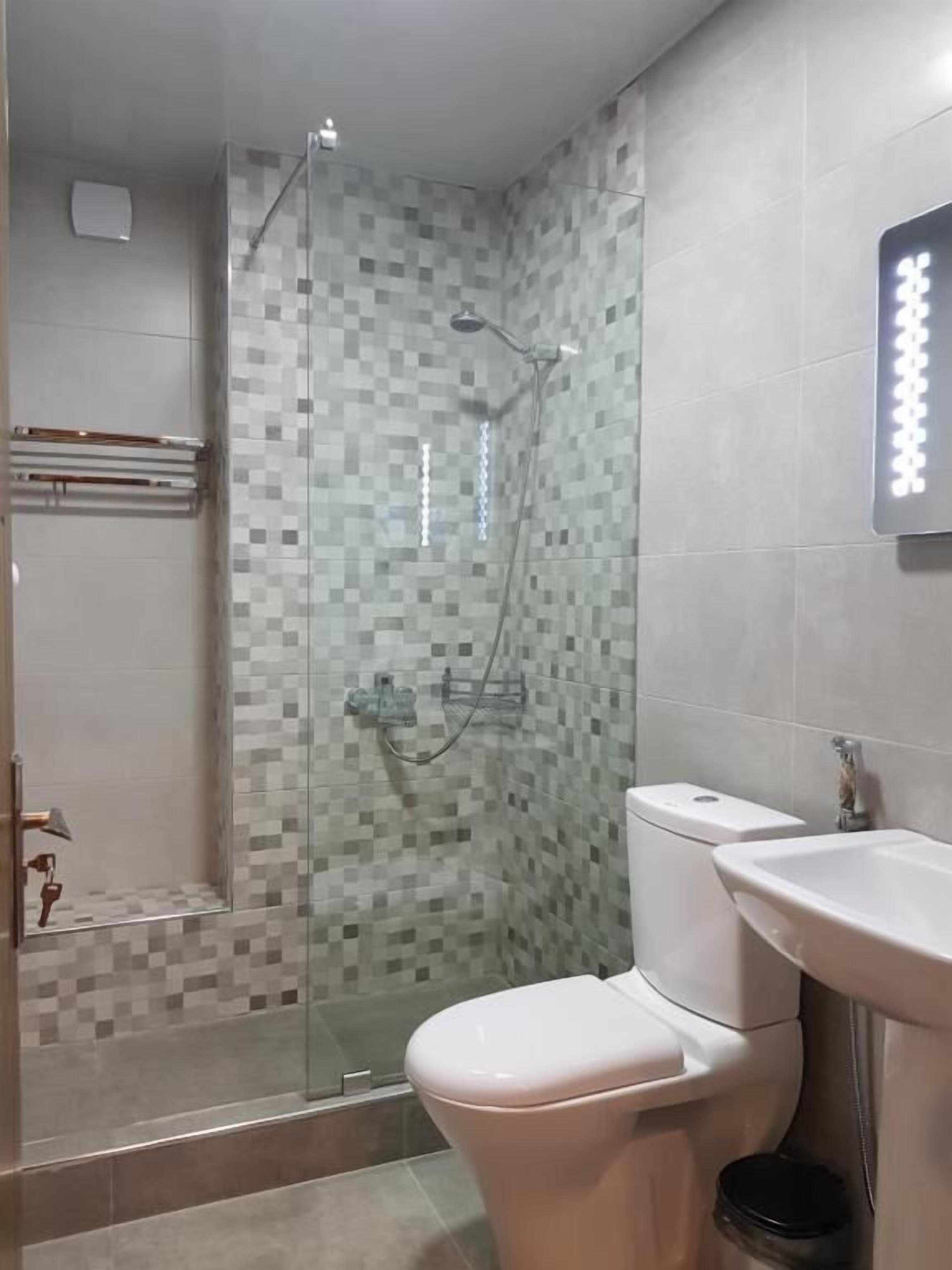 Un baño con ducha de vidrio, inodoro y lavabo.
