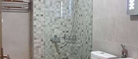 Un baño con ducha de vidrio, inodoro y lavabo.